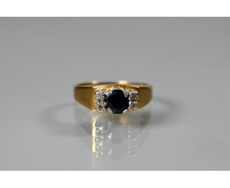 An 18ct yellow gold ring set central oval dark blue sapphire with two small diamonds to each side, size K, approx 4.7g all in