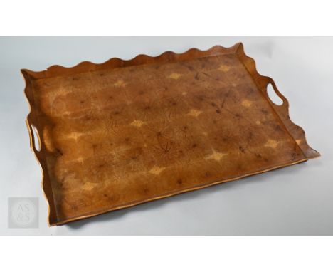 A vintage oyster laburnum/yew veneered tray with raised wavy rim and pierced end handles, 63 x 42 cm
