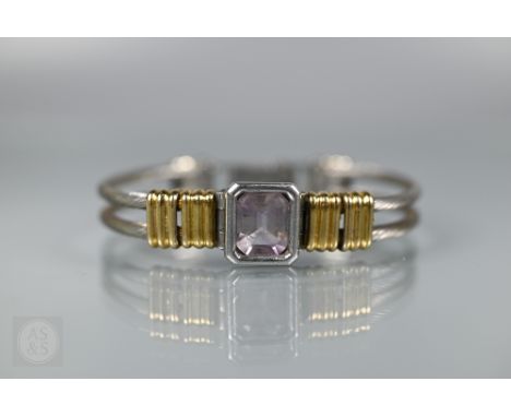A half-hinged bangle formed of two brushed cable wires linked by yellow metal bands with a central rectangular pale pink tour