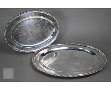 A graduated pair of heavy quality George V silver oval platters with gadrooned rims,&nbsp;Garrard &amp; Co. Ltd., London 1912