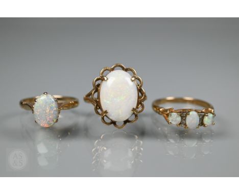 A three stone opal ring, the three pale white oval opals with two diamonds between, 9ct yellow gold set, size Q; a single ova