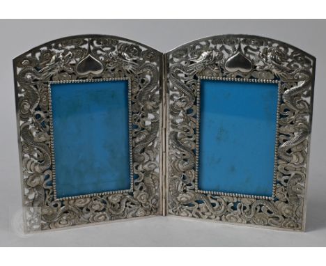 An antique Chinese export silver folding double photograph frame, richly embossed and chased with dragons in clouds, with sim