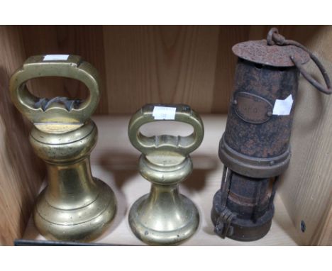 Two large bell weights, together with a miner's lamp
