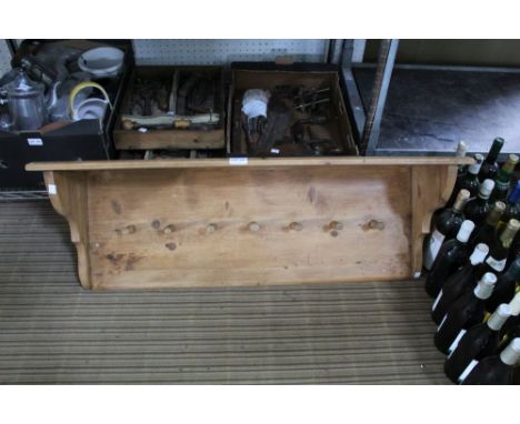 An old pine wall mounted coat rack with seven pegs and shelf above