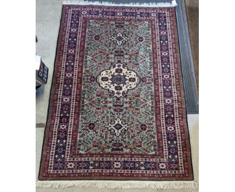 A Persian hand woven rug having a central motif and birds amongst flowers on a green field, surrounded by multiguard borders 
