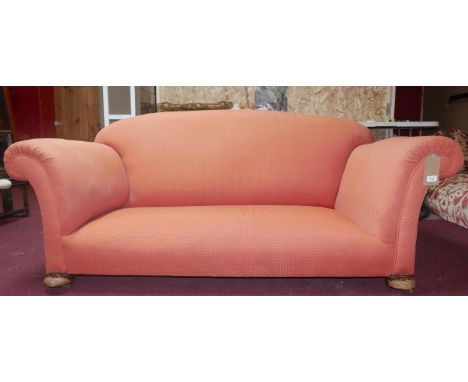 An early 20th century club sofa raised on bun feet and castors 