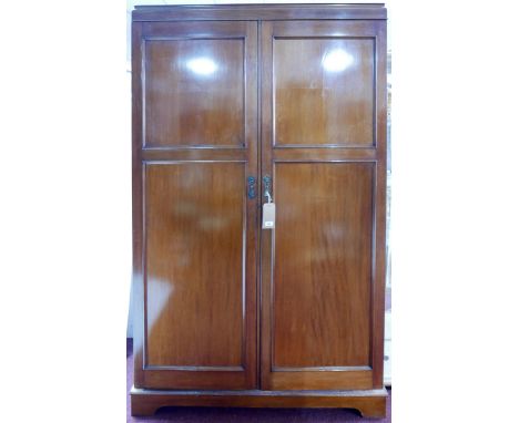 An early 20th century mahogany wardrobe, two doors enclosing hanging space, labelled drawers, some glass fronted, raised on b