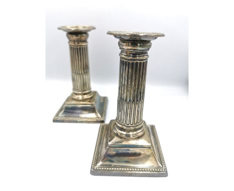 A pair of Victorian weighted silver candlesticks of classical fluted column form on square bases with beaded borders. Hallmar