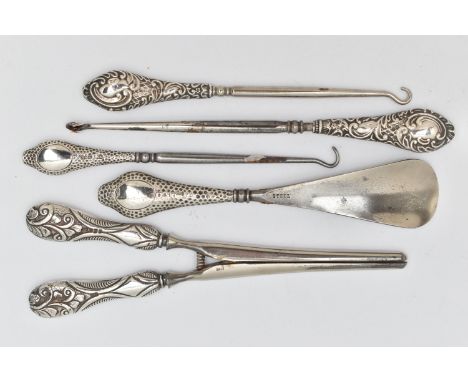 FIVE SILVER HANDLED ITEMS, to include three button hooks, a shoe horn and a pair of glove stretchers, each with a full silver