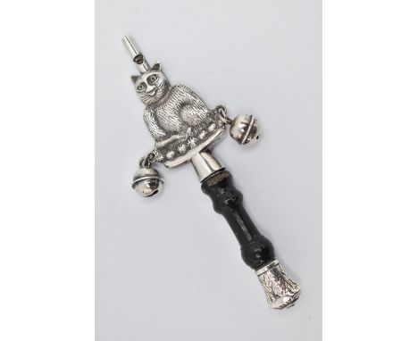 A WHITE METAL BABY RATTLE, in the form of a cat, fitted with two bells either side and a whistle to the terminal, carved wood
