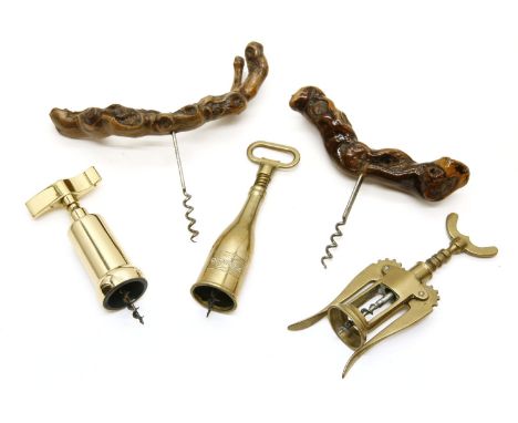 Two vintage driftwood handled corkscrews, together with three brass barrel corkscrews, one modelled as a champagne bottle, on