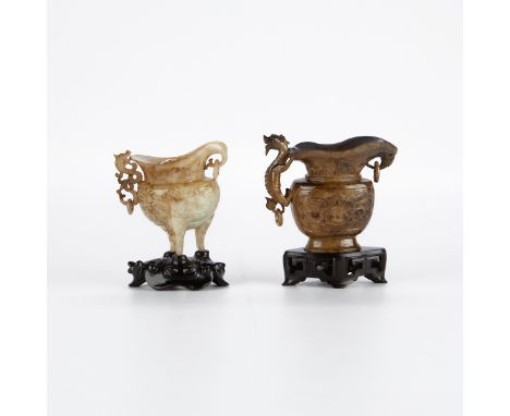 Group of two Chinese carved jade ewers in archaic forms. One tripod ewer, and one with incised taotie masks to the body and a