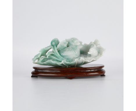 Chinese jade carving depicting a duck among lotus leaves and blossoms, of mottled white and green jade. The carving rests on 