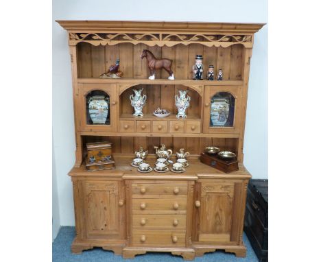 A 20th century pine dresser, the top with carved frieze over open shelf above five small drawers beneath open shelf between g