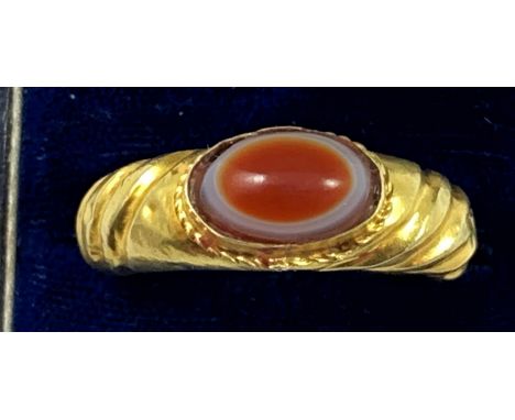 A gold Roman style ring, collet set with a cabochon sardonyx, ribbed tapering shank, size W, weight 6 gms (presumed filled wi