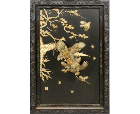 A Chinese hardwood and mother of pearl panel, c.1900, comprising a pair of fighting eagles amongst branches in high relief, r