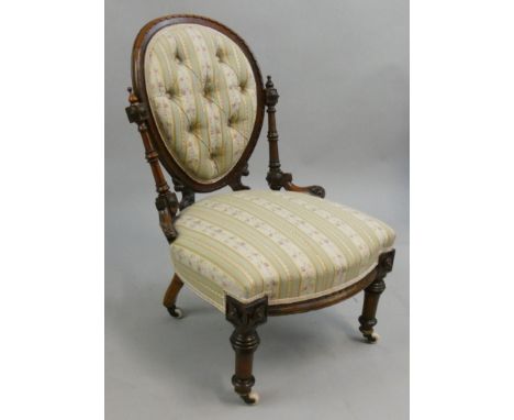A Victorian mahogany nursing chair, with button spoon back, raised on turned supports, porcelain and brass castors.