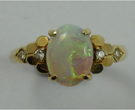 A gold, opal and diamond dress ring, stamped 585, claw set with a cabochon stone flanked by brilliant cuts, size O.