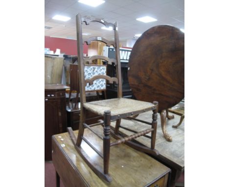 A Late XIX Century Oak Rocking Chair, with ladder back rails, rushed seat, on rockers.