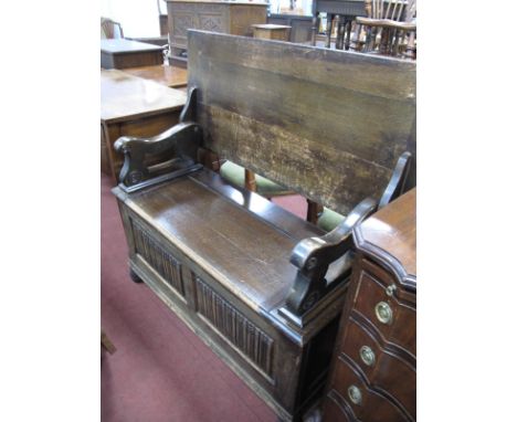 A XX Century Oak Monks Bench, with a folding back, hinged seat, linen fold panels on bun feel, 106cms wide.