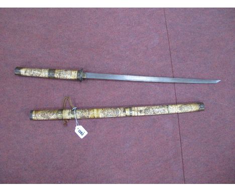 A Japanese Sword, with brass mounts to bone handle plus scabbard heavily carved with fourteen figures, 90cm overall length.