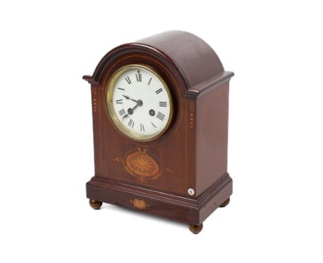An Edwardian mahogany mantel clock. The white enamel dial with Roman numerals, within a domed mahogany case with inlaid detai