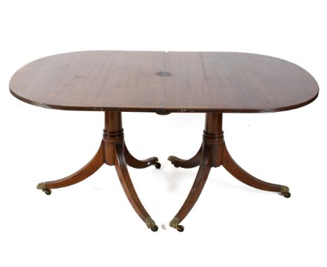 A Regency style D-end twin pedestal extending dining table. Having a cross banded mahogany top, and reeded tripod supports te