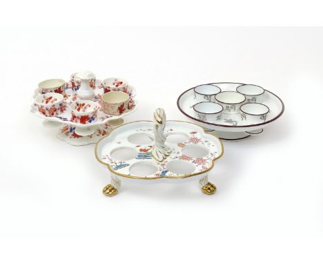 Three English porcelain egg cruets or stands  19th century, one of circular form, printed with black flower sprays and set wi