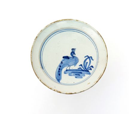 A delftware dish  c.1720, probably London, naively painted in blue with a peacock beside simplistic foliage, 23cm. 