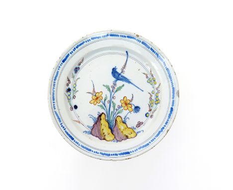 A Bristol delftware plate  c.1720-40, painted with a bird perched on a feathered foliate frond above flowers and rockwork ena