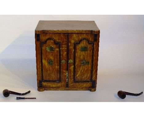 An Edwardian oak smokers cabinet, with two panelled doors, decorated with brass mounts and cartouche, enclosing fitted drawer