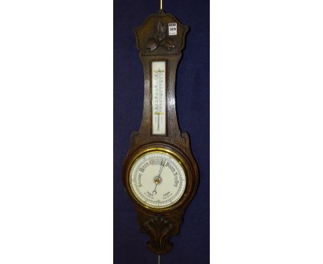 An oak cased barometer, with thermometer gauge to top and foliate carved decoration to top and bottom, 73cm long