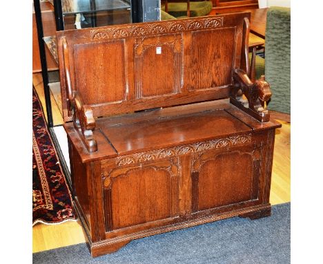 An oak monks bench, with swivel top raised on carved lion terminals and hinged seat, 100cm high x 96cm wide x 42cm deep