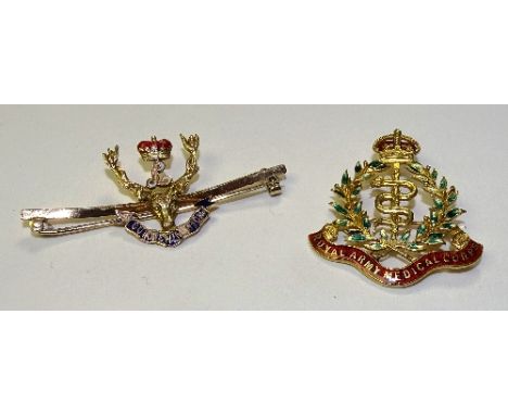 Two gold and enamel military badges, one for the Royal Army Medical Corps with snake between laurel wreaths and crown to top,