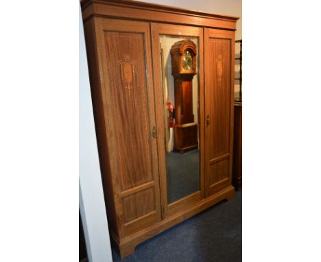 An Edwardian mahogany inlaid wardrobe, with moulded cornice above mirrored door, flanked with a panelled door, 210cm high x 1