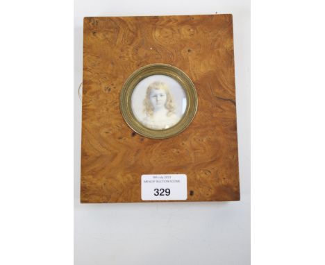 An Edwardian tondo miniature : A watercolour on ivory portrait of a young girl. In a burr walnut easel frame with silk back a