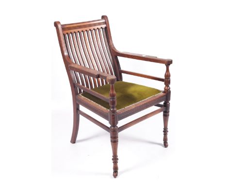 A James Shoolbred &amp; Co, Arts and Crafts walnut open armchair. With shaped comb back and front turned supports and impress