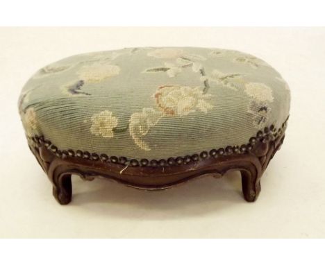 A small Victorian tapestry footstool with carved apron and  feet