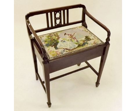 An Edwardian mahogany piano stool with raised back and arm supports and rise top tapestry seat