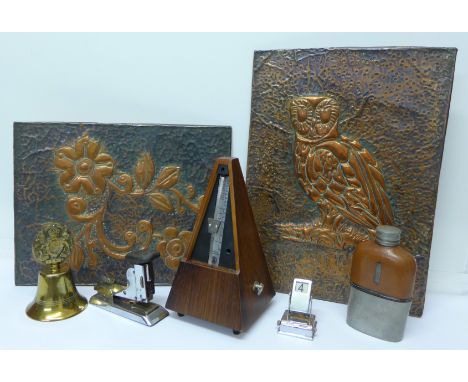 A metronome, hip flask, bell, perpetual calendar, stapler and two copper plaques