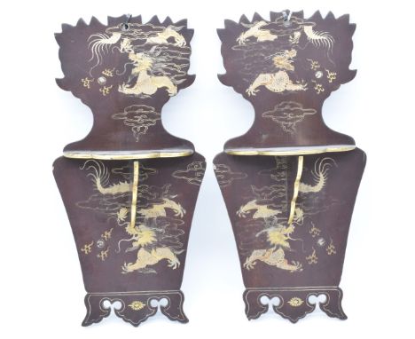 A pair of Japanese Meiji period lacquer wall brackets with folding shelves and gilt decoration depicting a dragon chasing a f
