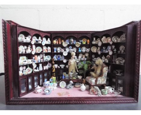 Dolls House - a glass fronted and top wooden frame antique shop complete with ceramic contents and furniture, appears to be i