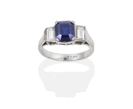 A Sapphire and Diamond Ring, an octagonal cut sapphire in a claw setting, to baguette cut diamond set shoulders, total estima