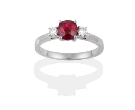 An 18 Carat White Gold Ruby and Diamond Three Stone Ring, the cushion shaped ruby between two round brilliant cut diamonds in