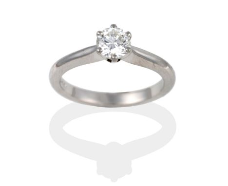 A Platinum Diamond Solitaire Ring, the round brilliant cut diamond in white claws to a tapered shoulder plain polished shank,