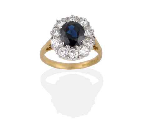 An 18 Carat Gold Sapphire and Diamond Cluster Ring, the oval mixed cut sapphire within a border of round brilliant cut diamon