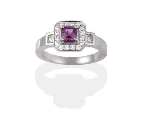 An 18 Carat White Gold Pink Sapphire and Diamond Cluster Ring, the cushion cut pink sapphire claw set above a border of round