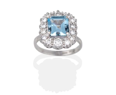 An Aquamarine and Diamond Cluster Ring, an octagonal cut aquamarine in a claw setting, within a border of vari-sized round br
