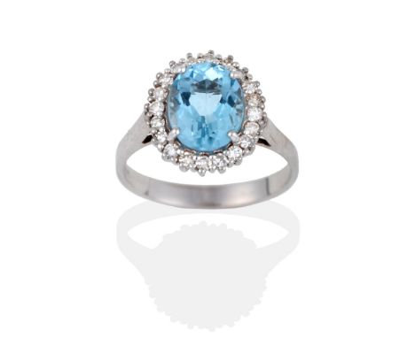 An Aquamarine and Diamond Cluster Ring, the oval cut aquamarine within a border of eight-cut diamonds in white claw settings,