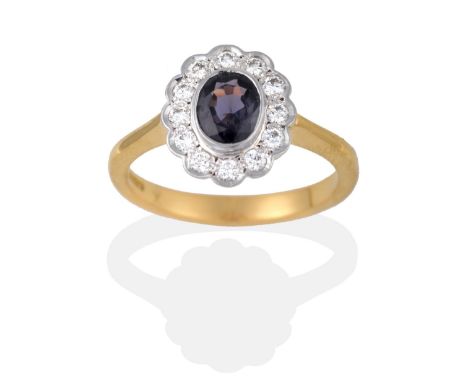 An 18 Carat Gold Colour-Change Sapphire and Diamond Cluster Ring, the oval mixed cut sapphire in a white rubbed over setting 